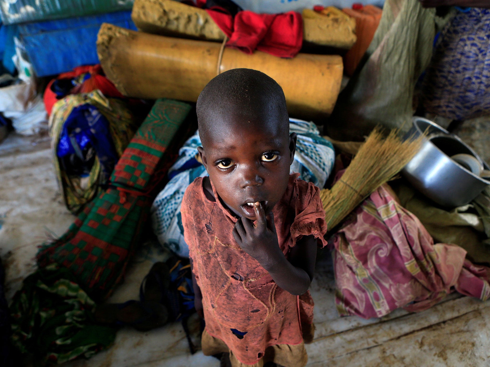 A displaced boy from South Sudan stands next to family belongings in Lamwo after fleeing fighting in Pajok town across the border in northern Uganda