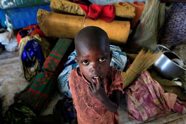 A displaced boy from South Sudan stands next to family belongings in Lamwo after fleeing fighting in Pajok town across the border in northern Uganda