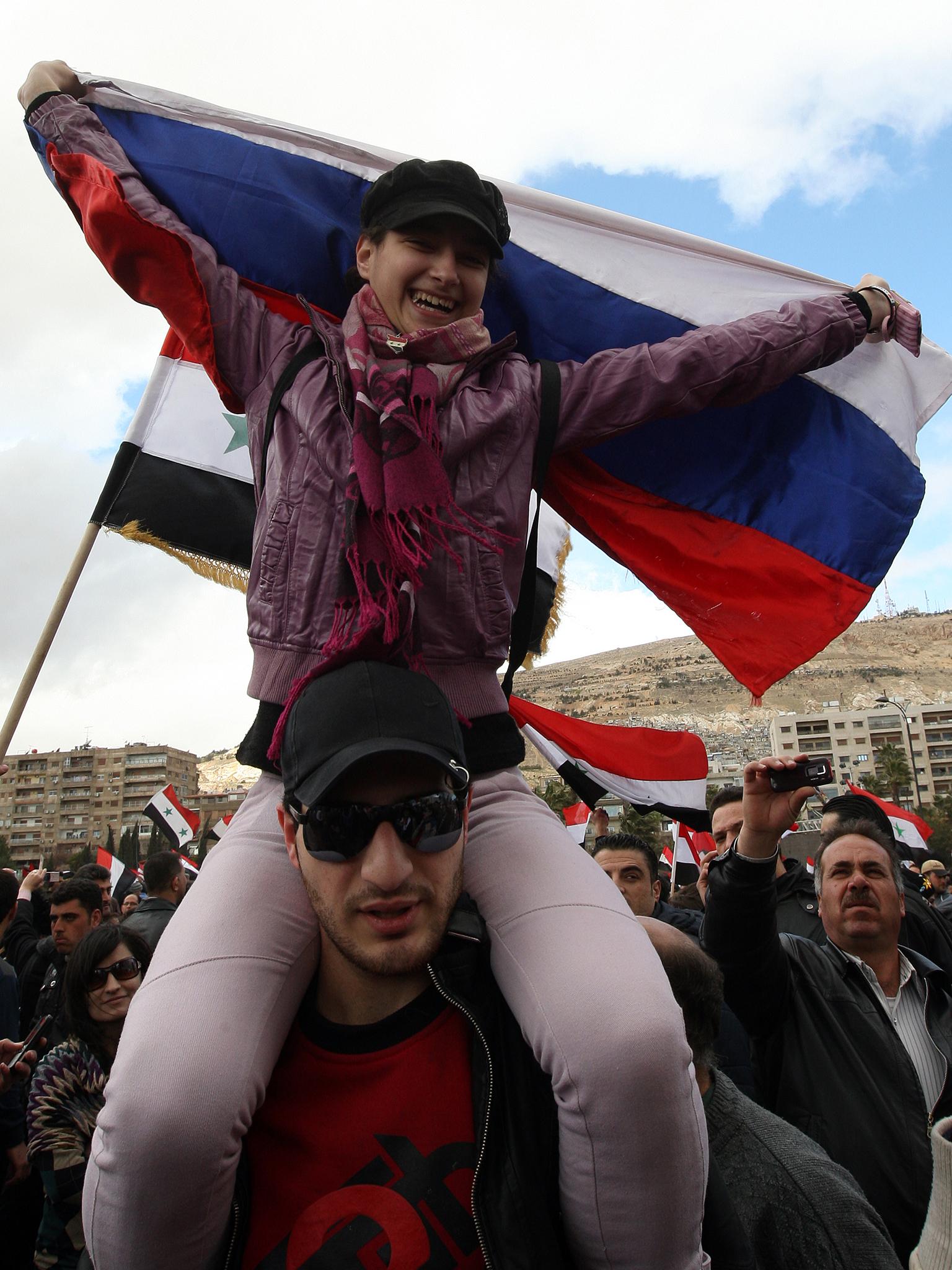 A Syrian girl holds a Russian flag during a rally in support of President Bashar al-Assad on the first anniversary of the anti-regime revolt in Damascus