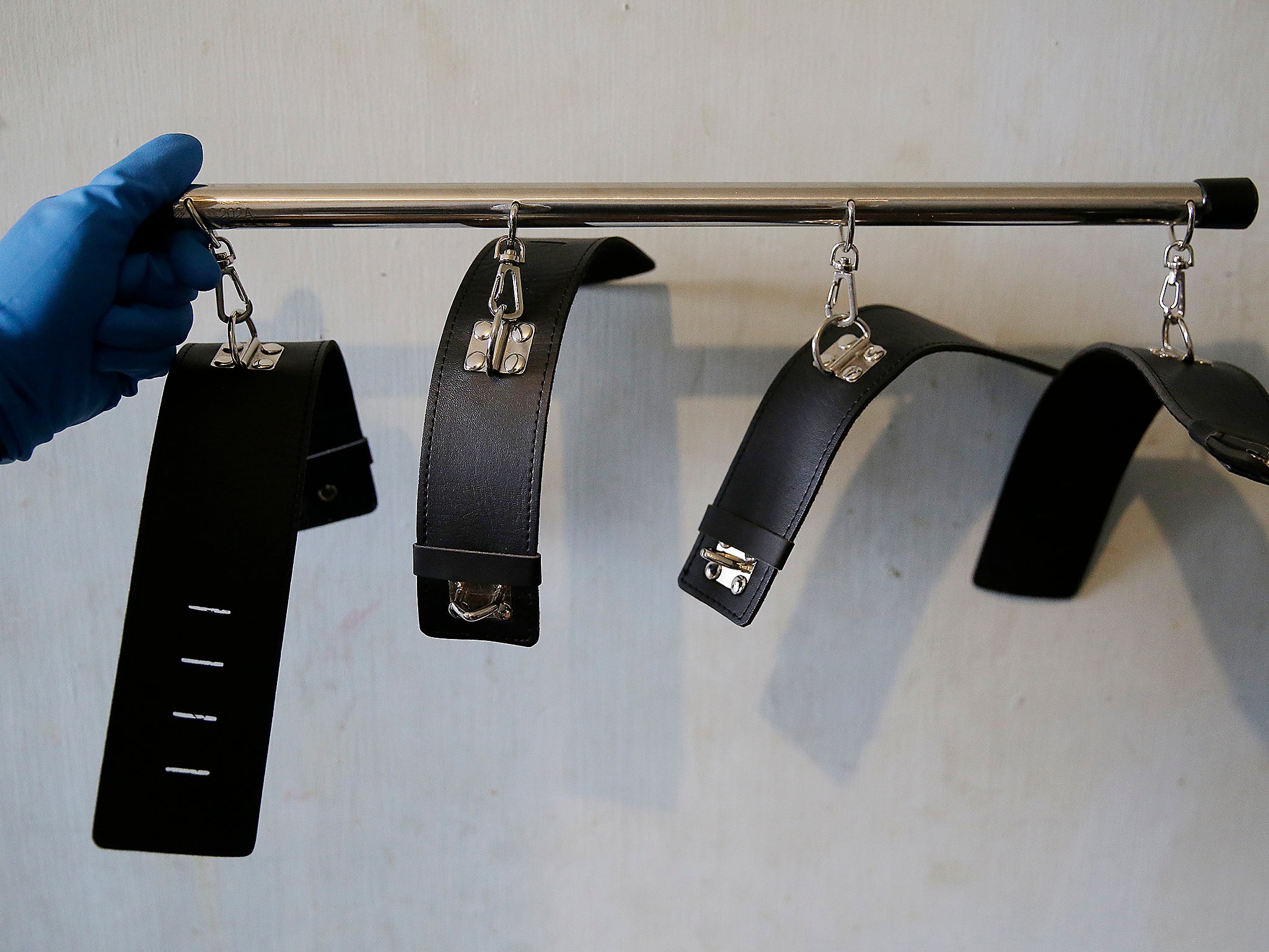 A member of the National Bureau of Investigation Anti-human Trafficking division displays bondage cuffs used for sexual acts found during the raid (AP/Aaron Favila)