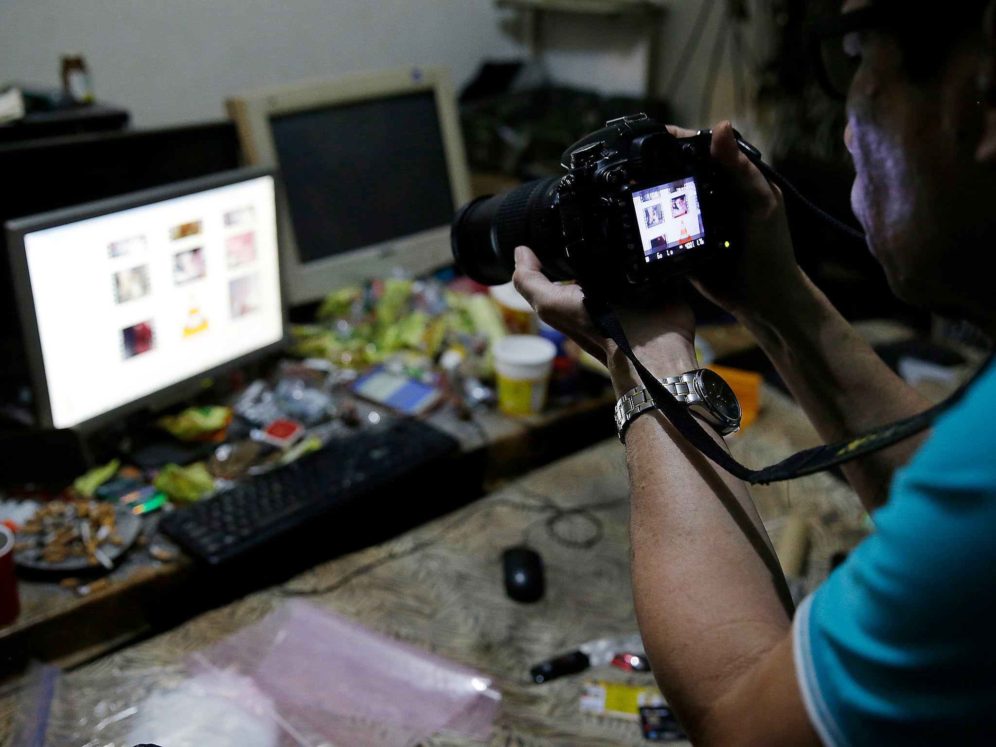 A Filipino member of the National Bureau of Investigation takes a picture of the computer of suspected child webcam cybersex operator, David Timothy Deakin, during the raid (AP)