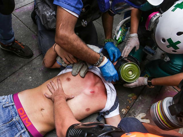 Demonstrators help another protestor during clashes with members of the National Bolivarian Guard (GNB) in Caracas, Venezuela