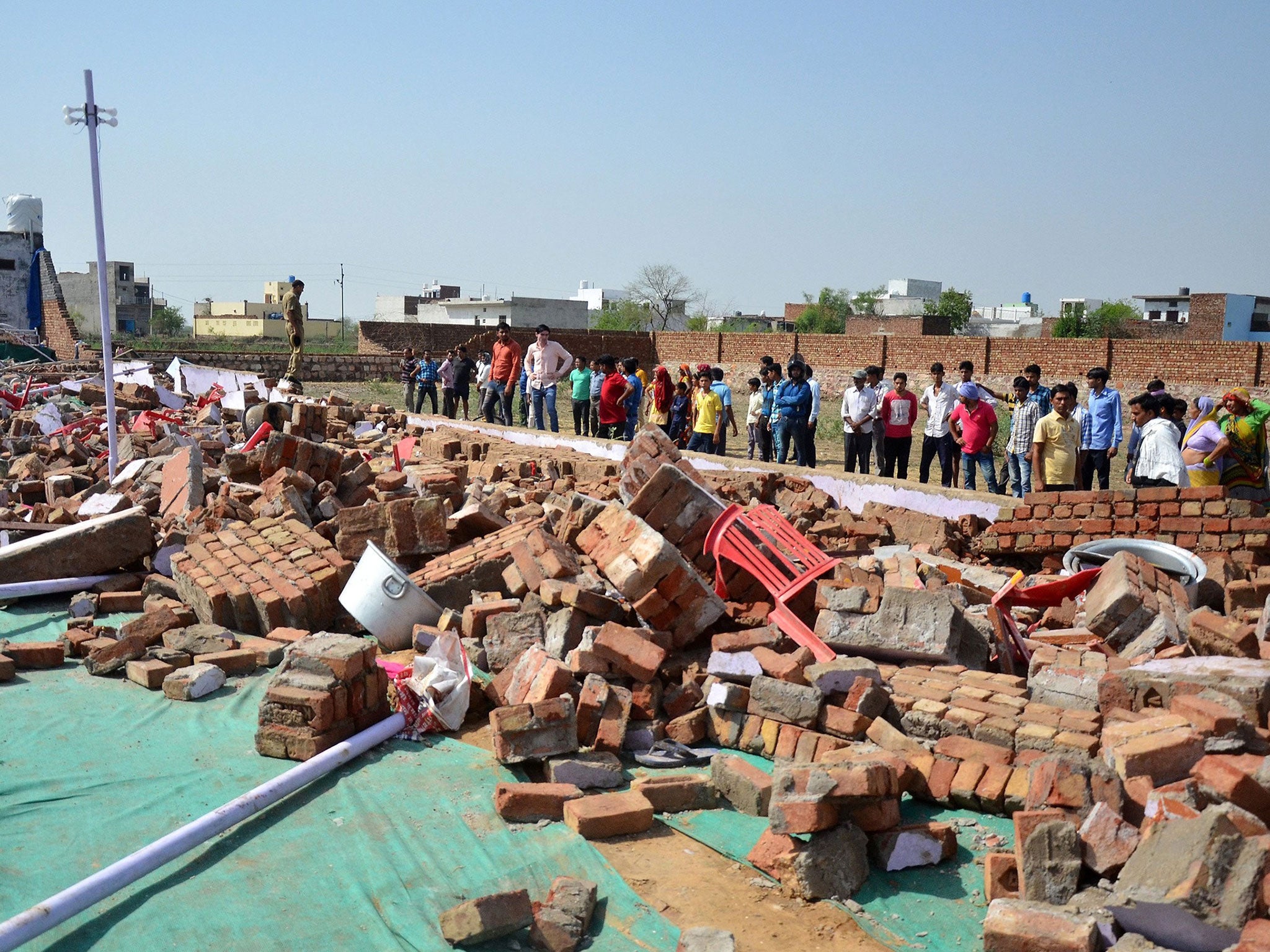 People gather near the debris where at least 24 people were killed when a wall collapsed at a wedding in the Bharatpur district of Rajasthan, India