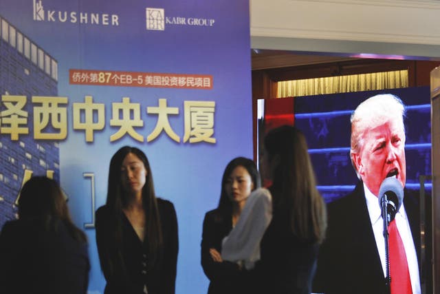 A projector screen shows footage of President Donald Trump during an investor event in China.