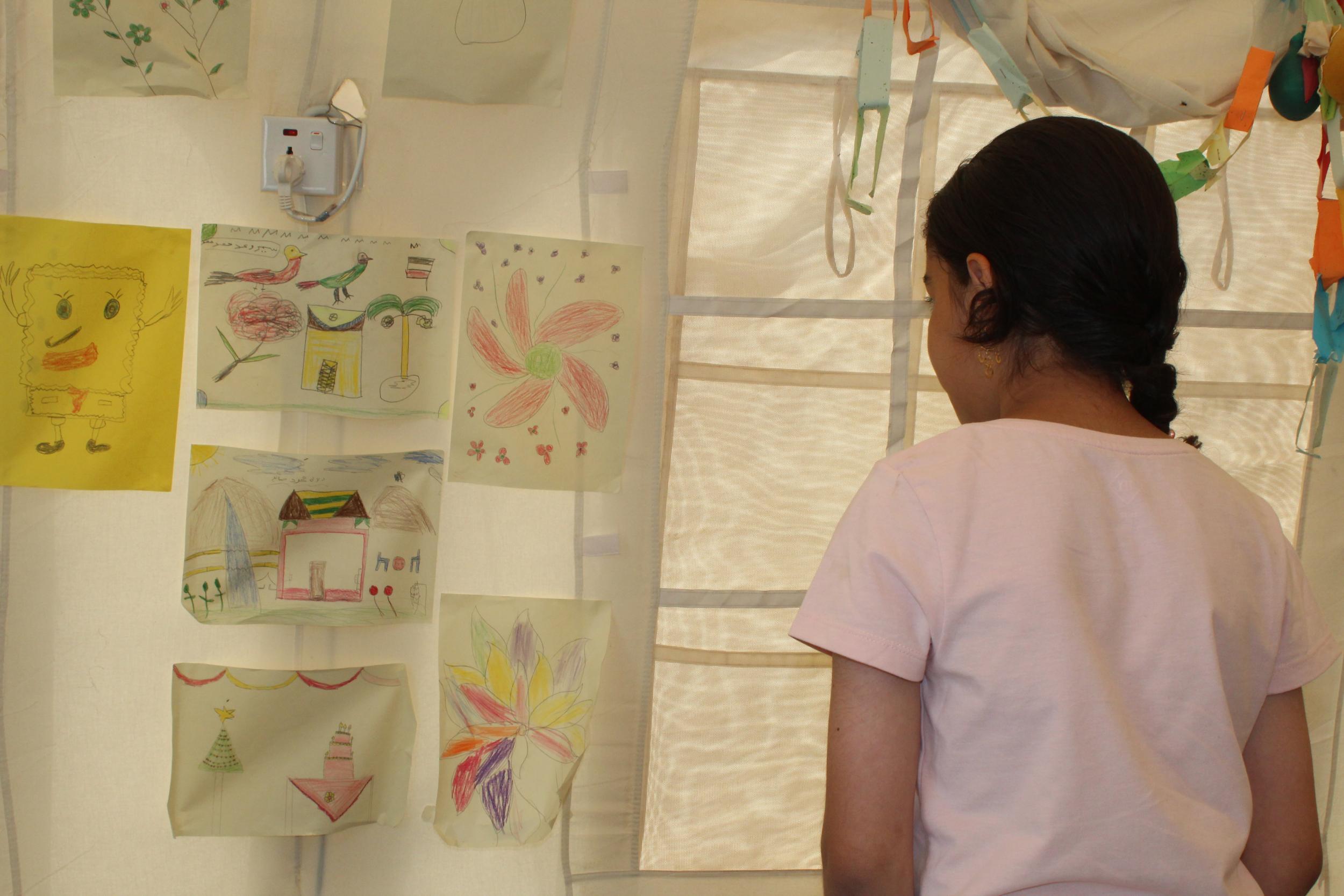 Ayesha (not her real name), looks at the drawings by other children at Hasensham IDP camp