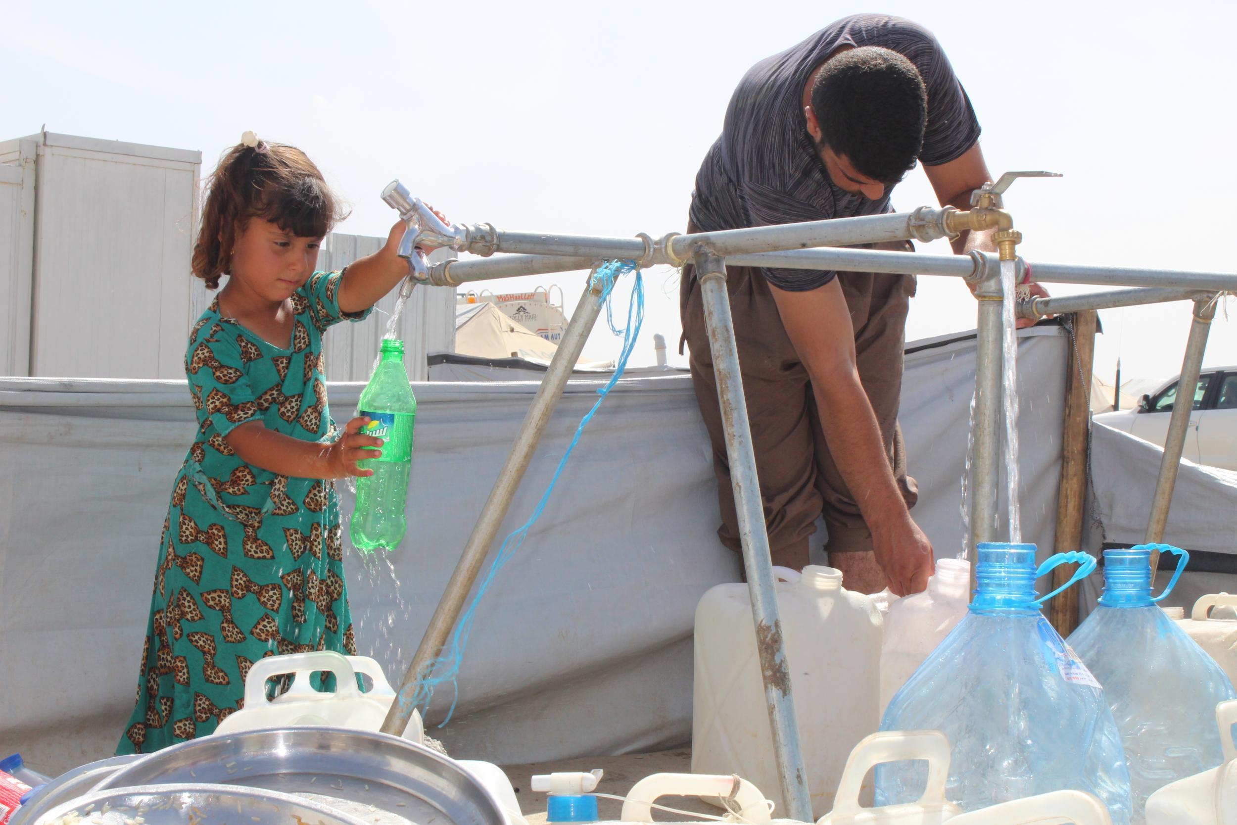 A little girl fills up a bottle with drinking water on 9 May 2017 in Hasensham IDP camp outside Mosul. Summer temperatures in Iraq hit a record 54 degrees Celsius last year