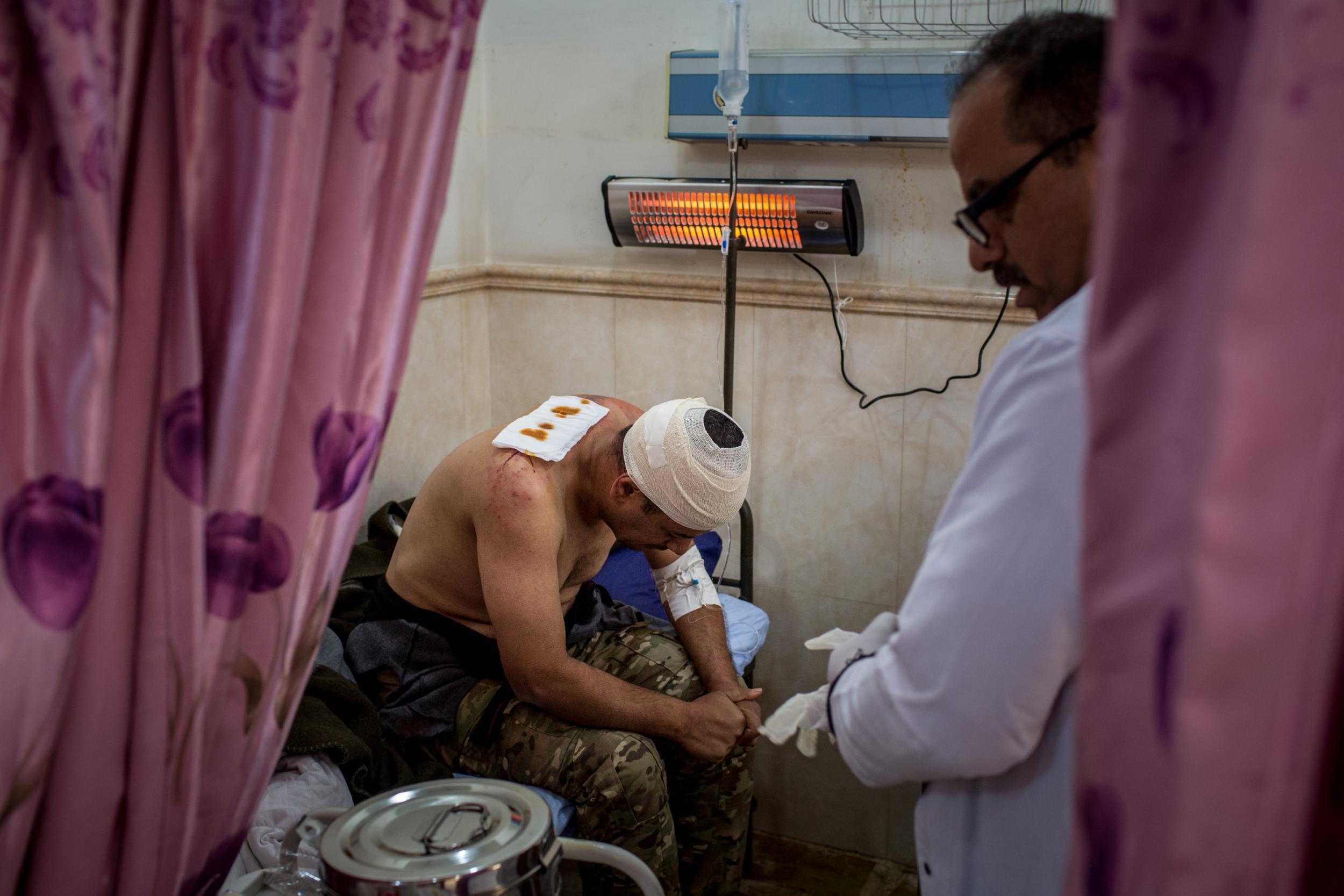 A doctor tends to a soldier injured in fighting in Qaraqosh in Mosul, Iraq