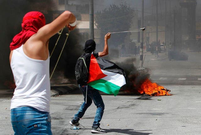 Protesters use a sling shot to throw stones towards Israeli security forces during clashes following a demonstration marking the 69th anniversary of the 'Nakba' in the West Bank town of Bethlehem, on 15 May 2017