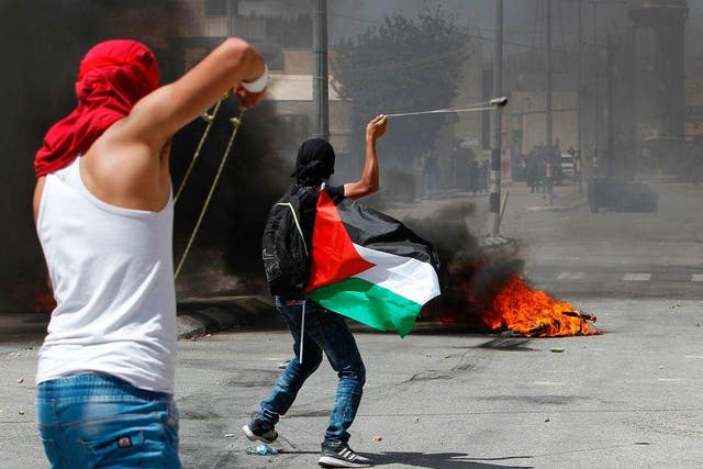 Protesters use a sling shot to throw stones towards Israeli security forces during clashes following a demonstration marking the 69th anniversary of the 'Nakba' in the West Bank town of Bethlehem, on 15 May 2017