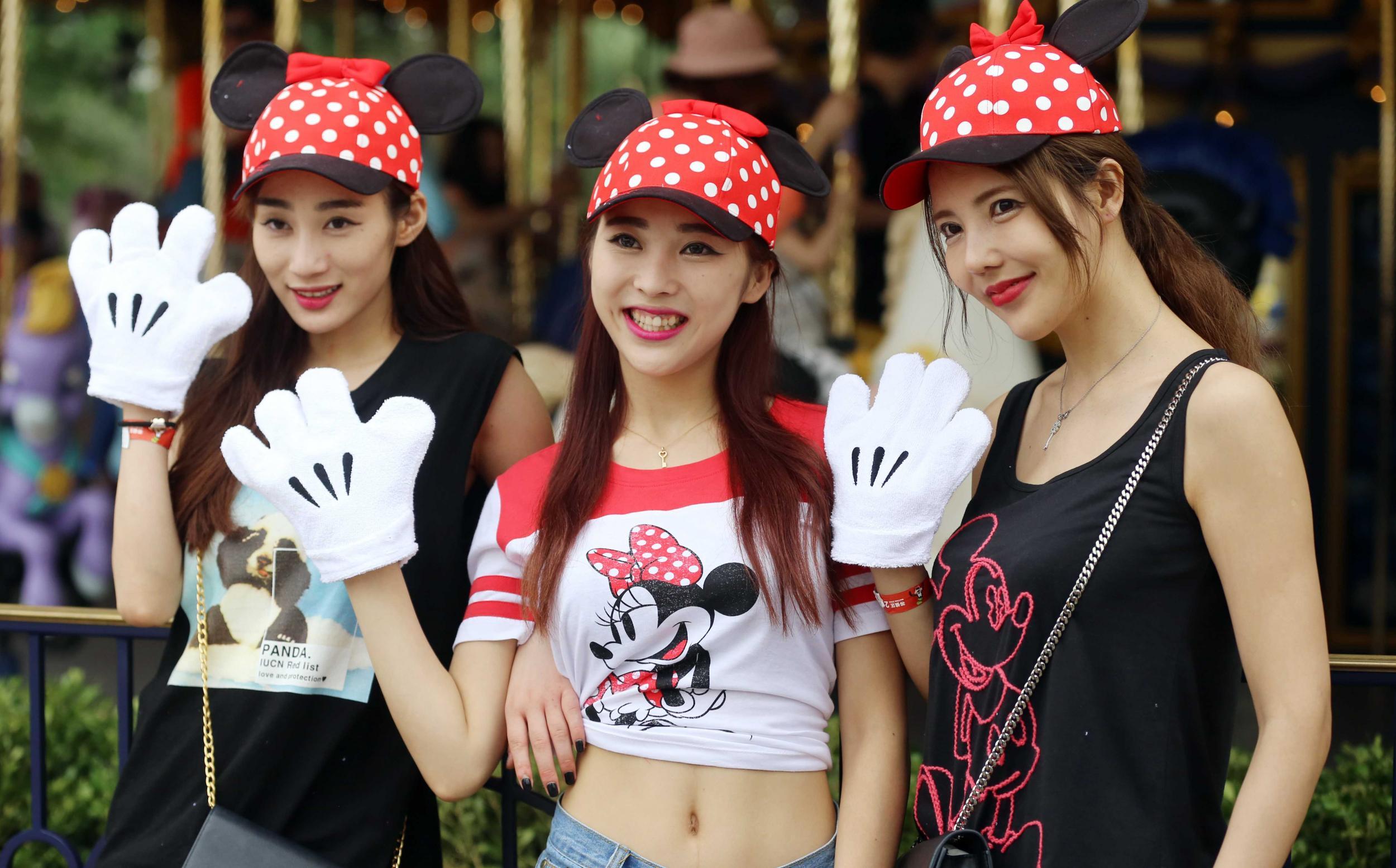 Women wearing Mickey Mouse and Minnie Mouse tee shirts and caps in the Shanghai Disneyland