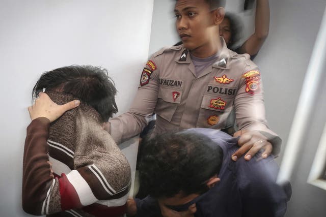 A police officer escorts two men accused of having gay sex into a holding cell prior to their trial at sharia court in Banda Aceh