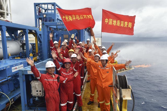 Workers celebrate the successful trial extraction of natural gas from combustible ice trapped under the seafloor on a drilling platform on the South China Sea