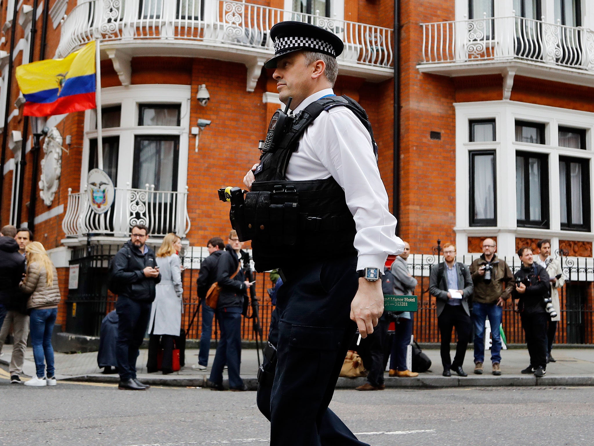 A police officer walks past people gathering outside the Ecuadorian embassy in London on 19 May