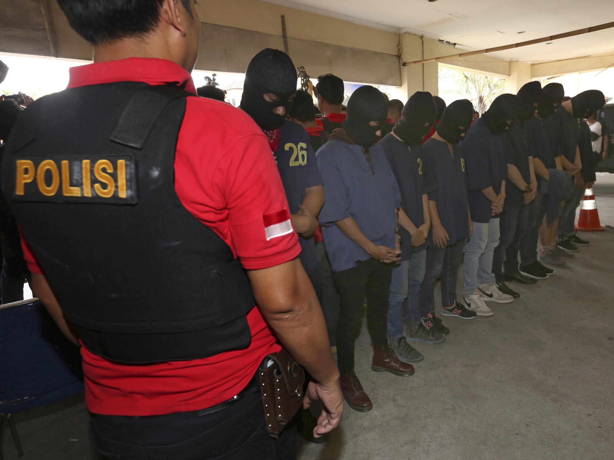 Police officers escort men arrested in a raid on a gay sauna at North Jakarta police headquarters