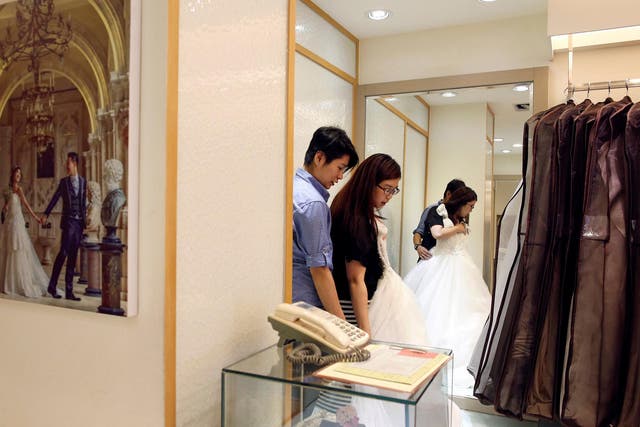 Daphne Chiang (right), an insurance consultant, tries on a wedding dress with her partner Kenny Jhuang, a service worker in Taipei