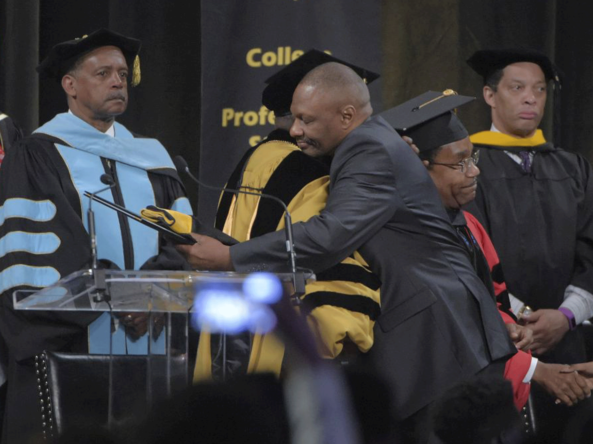 Bowie State University President Dr Mickey L. Burnim hugs Richard Collins Jr., father of Richard Collins III, at the school's graduation ceremony.