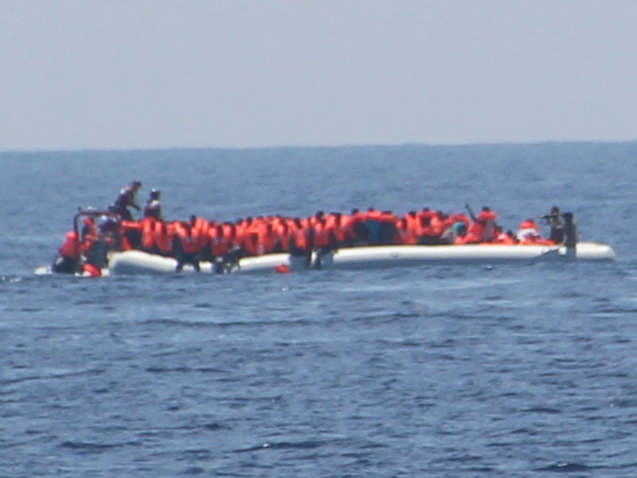 The crew of Jugend Rettet's Iuventa rescue ship photographed what appeared to be a Libyan coastguard officer pointing a weapon at refugees (far right)
