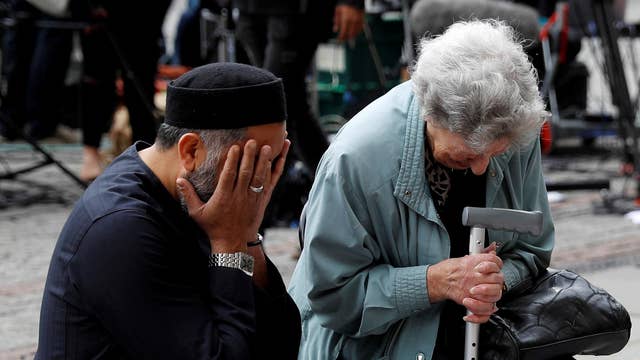 A Jewish woman named Renee Rachel Black and a Muslim man named Sadiq Patel react next to floral tributes in Albert Square