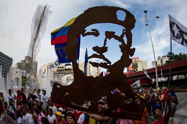 Supporters of Venezuelan president Nicolas Maduro hold a sign depicting late president Hugo Chavez during pro-government rally in Caracas