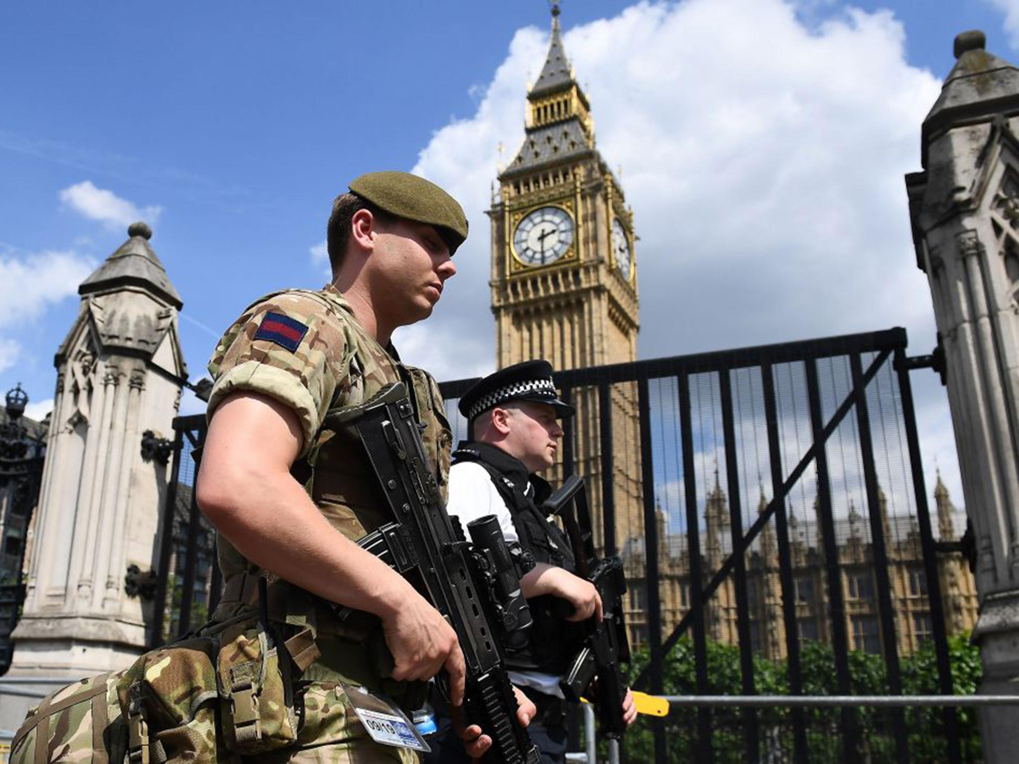 A soldier and armed policeman patrol along Whitehall near Downing Street yesterday