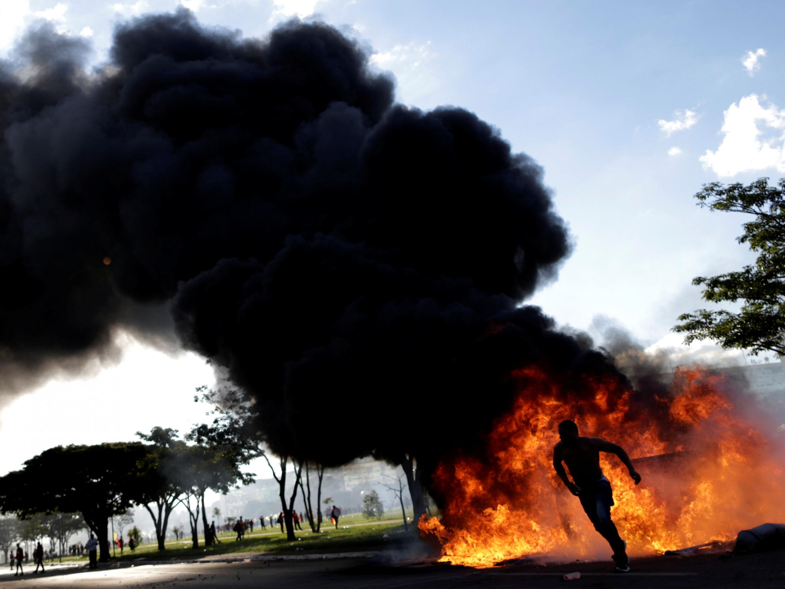 A demonstrator runs from a burning barricade during a protest against President Michel Temer and the latest corruption scandal to hit the country in Brasilia