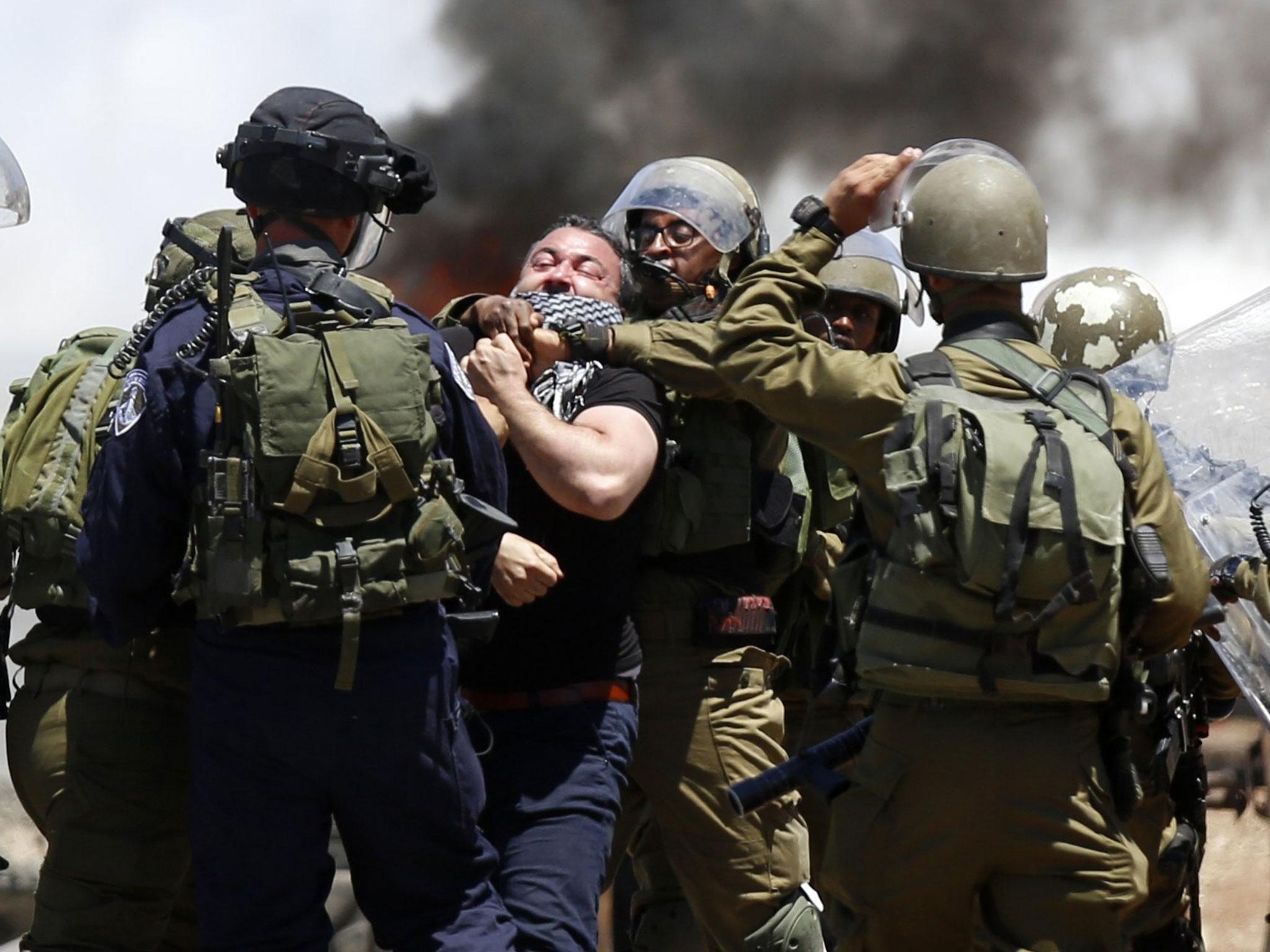 Israeli soldiers arrest a Palestinian man protesting in support of prisoners on hunger strike in Israeli jails, in the West Bank village of Beita