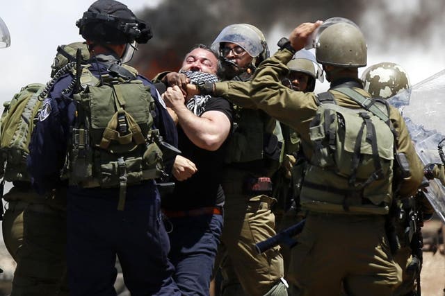 Israeli soldiers arrest a Palestinian man protesting in support of prisoners on hunger strike in Israeli jails, in the West Bank village of Beita