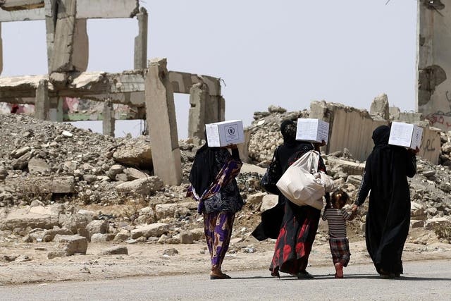 Iraqi women walk past destroyed buildings south of Mosul on 26 May 2017