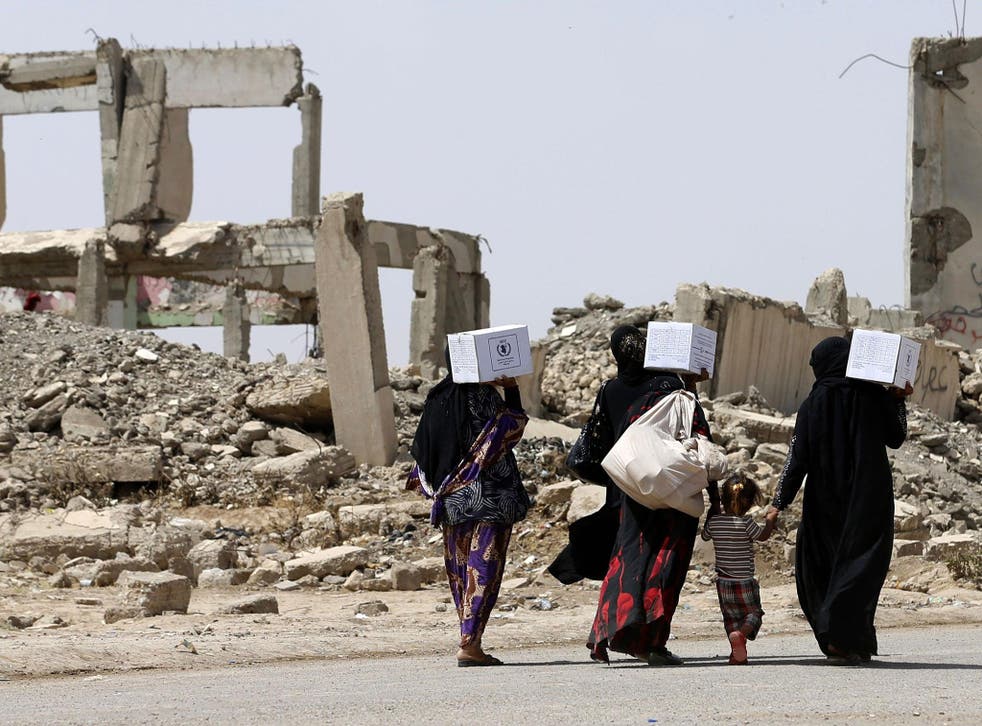 Iraqi women walk past destroyed buildings south of Mosul on 26 May 2017