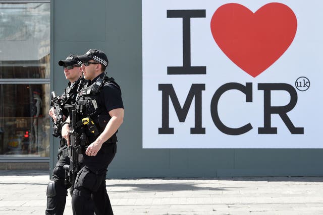 Police walk past a huge message of support following the Manchester attack, outside the Manchester Arena Complex in Manchester on May 27, 2017