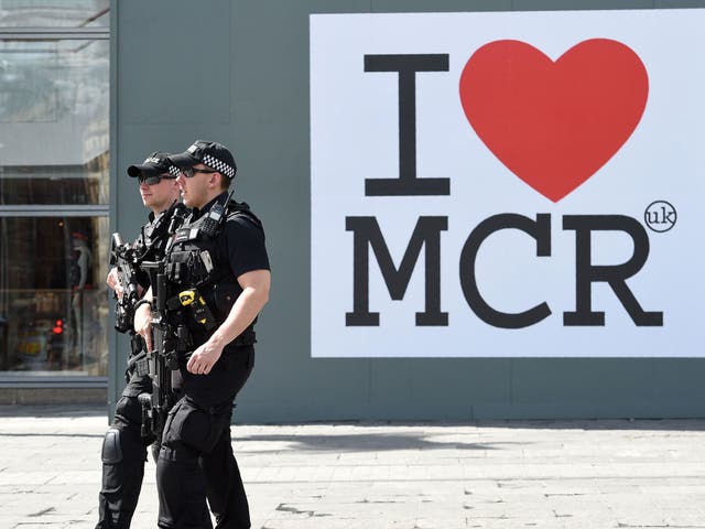 Police walk past a huge message of support following the Manchester attack, outside the Manchester Arena Complex in Manchester on May 27, 2017