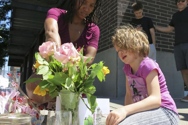 Angel Sauls, left, helps her stepdaughter Coco Douglas arrange a sign and some painted rocks she made for a memorial in Portland, Oregon, in memory of the two bystanders who were stabbed to death on Friday while trying to stop a man who was yelling anti-Muslim slurs and acting aggressively toward two young women
