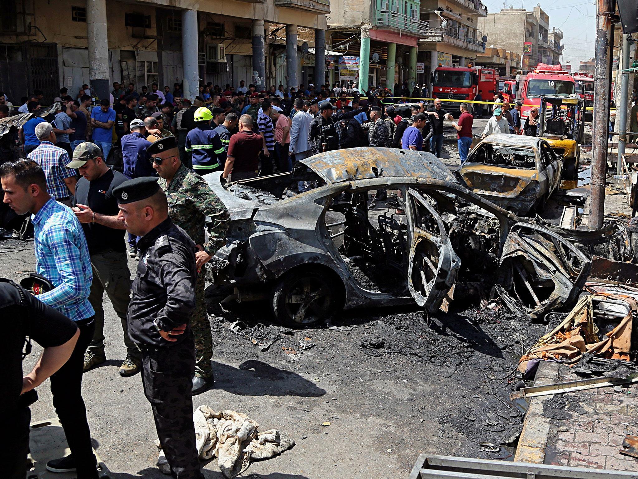 Iraqi security forces and civilians inspect the site of the second deadly bomb attack in Baghdad, Iraq