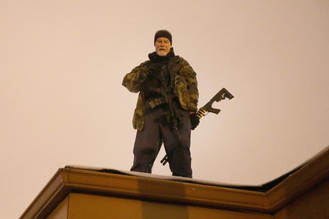 John Karriman. a volunteer from Oath Keepers, stands guard on the rooftop of a business in Ferguson, Missouri