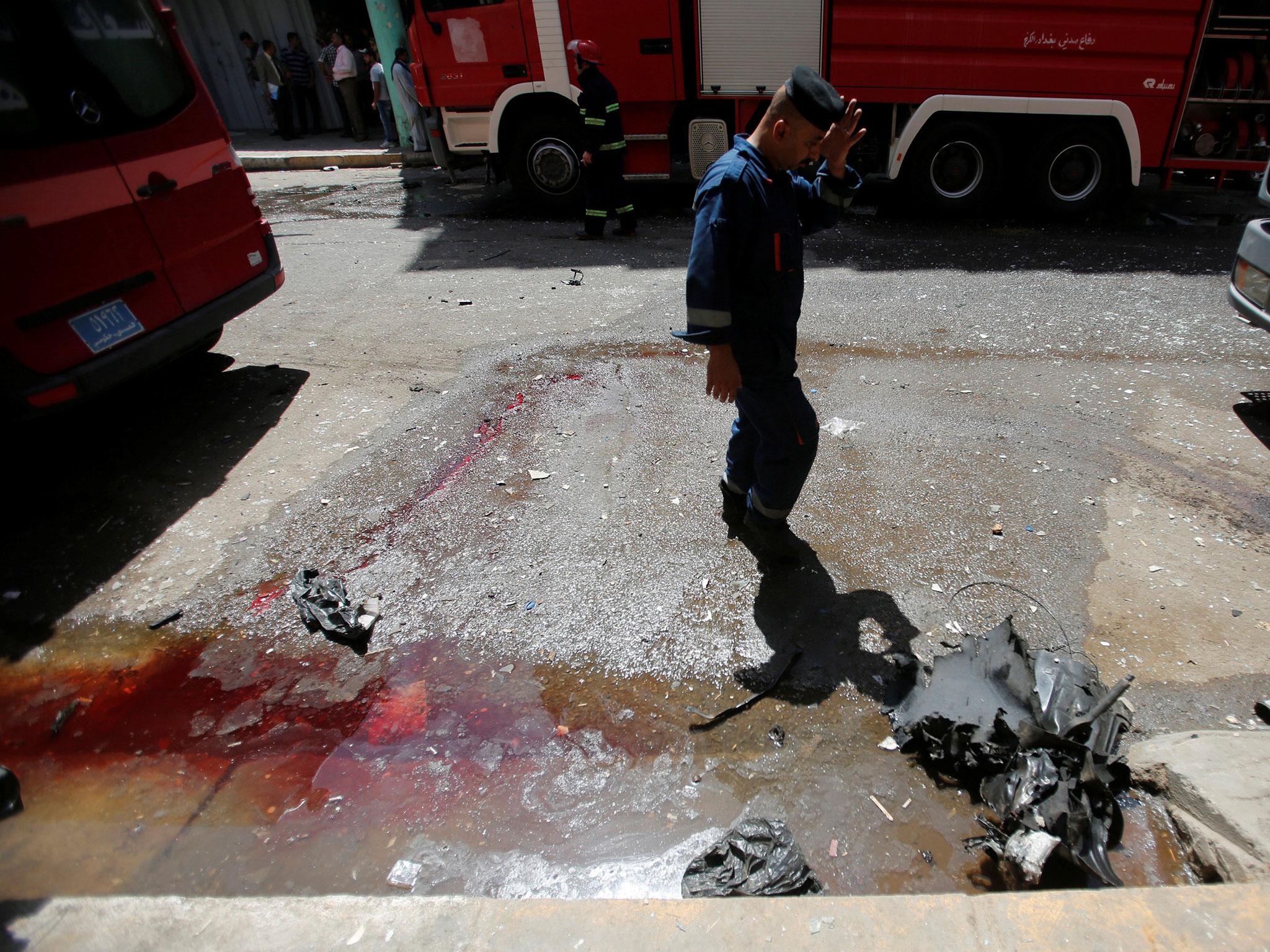 A firefighter inspects the site of the car bomb attack, near a government office in Karada district in Baghdad