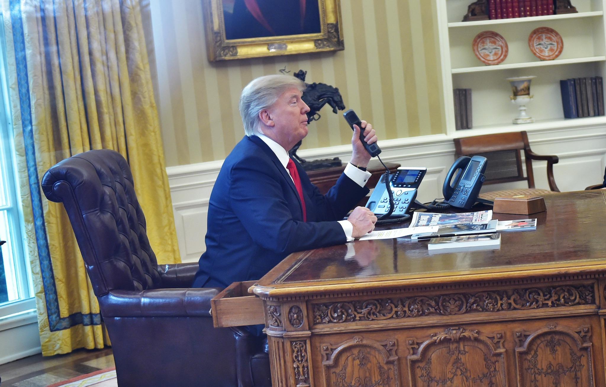 Donald Trump seen through an Oval Office window speaks on the phone to King Salman of Saudi Arabia