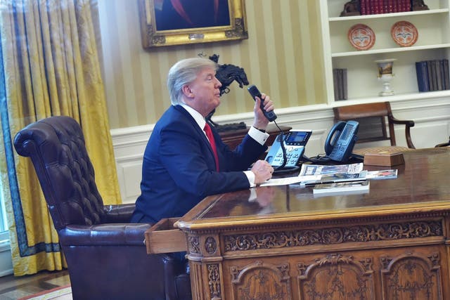 Donald Trump seen through an Oval Office window speaks on the phone to King Salman of Saudi Arabia