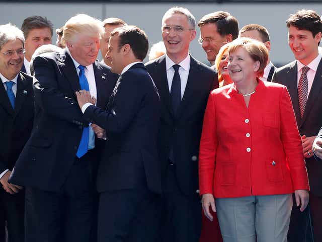 US President Donald Trump shakes hands with French President Emmanuel Macron as German Chancellor Angela Merkel laughs with fellow Nato leaders