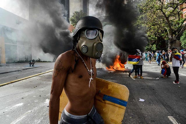 An opposition activist wears a helmet and gas mask during a protest against the government of Nicolas Maduro in Caracas