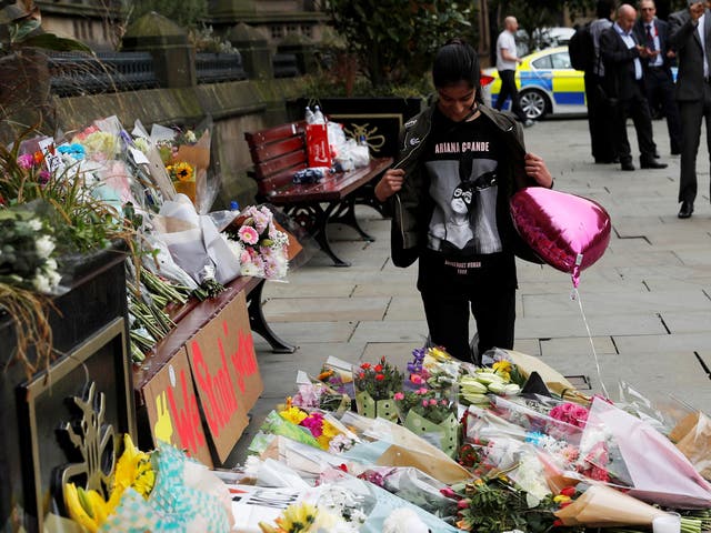 An Ariana Grande fan next to floral tributes in Manchester's St Ann Square