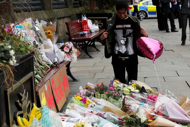 An Ariana Grande fan next to floral tributes in Manchester's St Ann Square