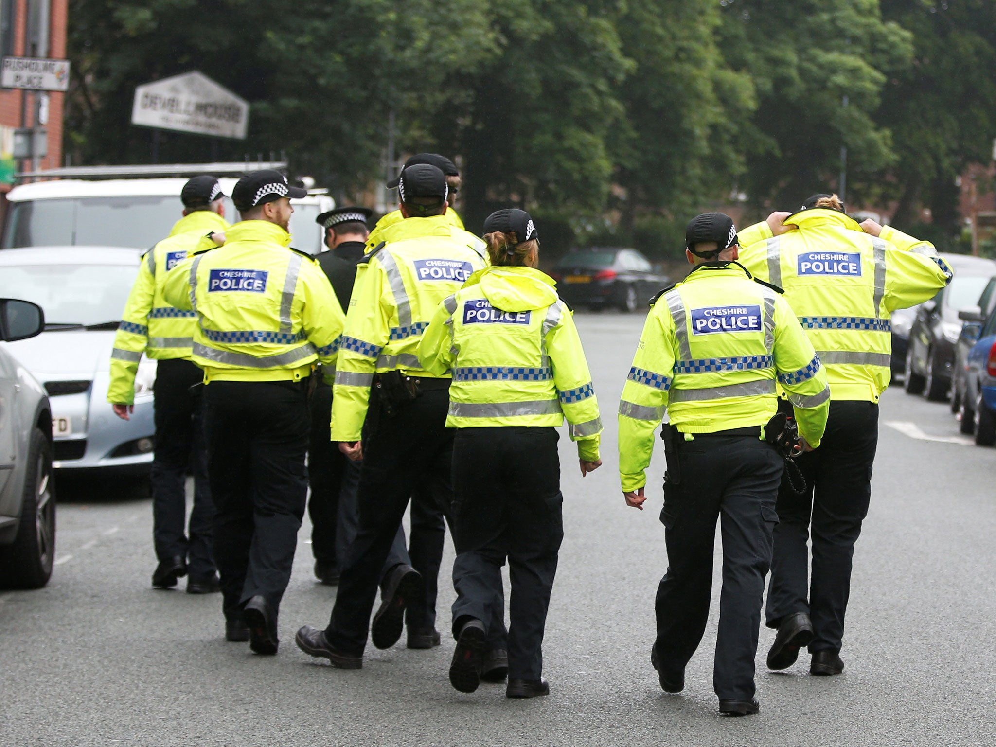 Police walk up the street towards Devell House, in Rusholme, Manchester, on 2 June