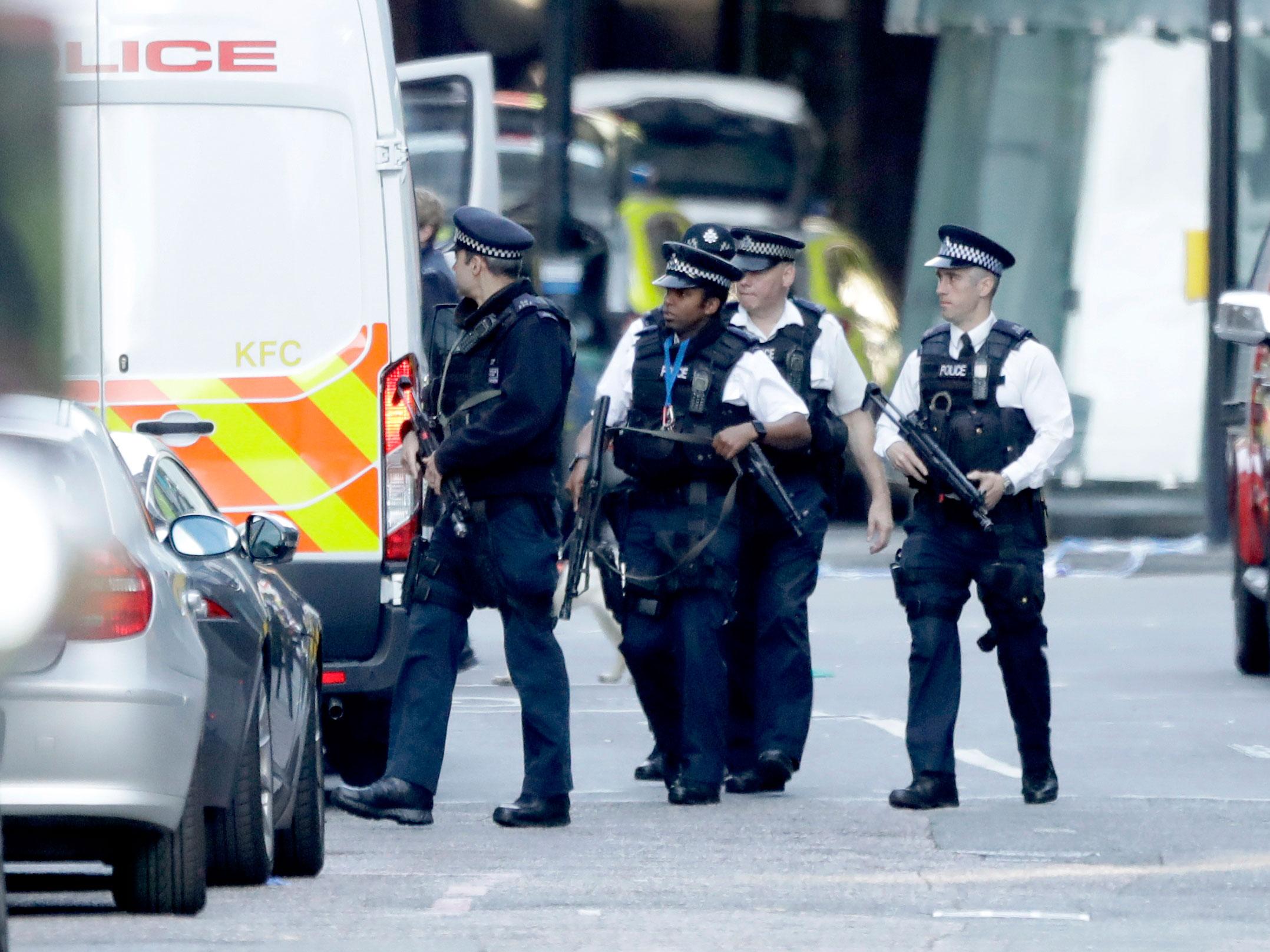 Armed British police officers walk within a cordoned off area after an attack in the London Bridge area of London