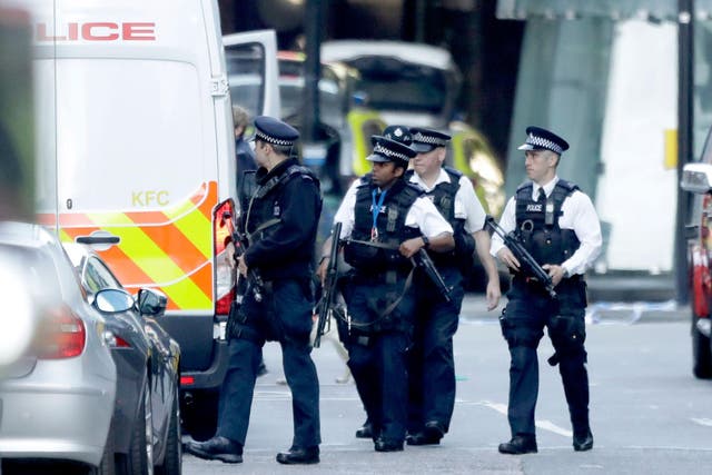 Armed British police officers walk within a cordoned off area after an attack in the London Bridge area of London