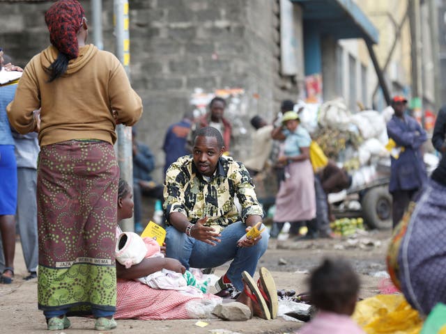 Kenyan social-political activist Boniface Mwangi (C) talks to a street hawker during his political campaign ahead of the August elections