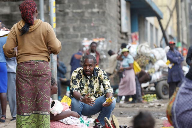 Kenyan social-political activist Boniface Mwangi (C) talks to a street hawker during his political campaign ahead of the August elections