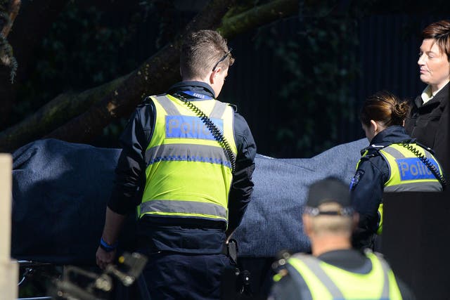 Police officers help the coroner remove a body at the scene of a hostage situation in the Melbourne bayside suburb of Brighton on June 6, 2017