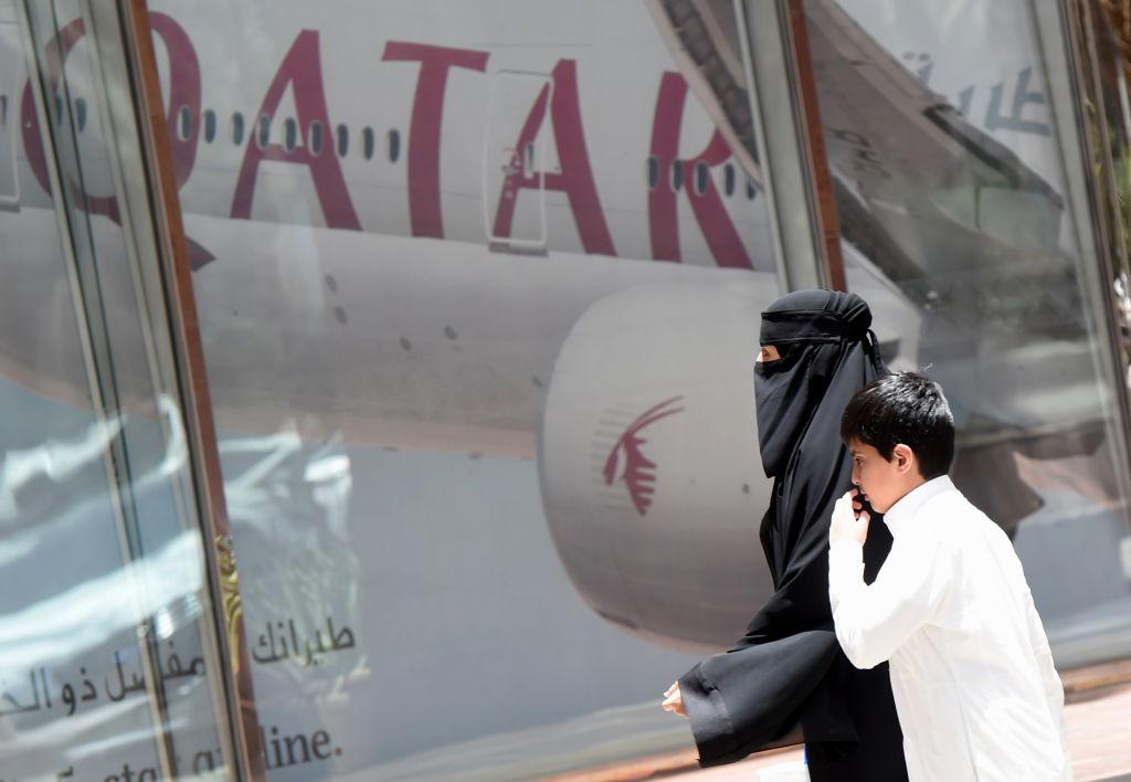 A woman and boy walk past a Qatar Airways branch in the Saudi capital of Riyadh