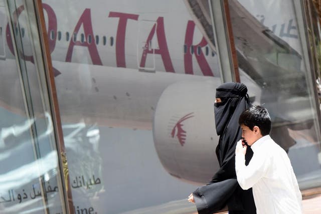 A woman and boy walk past a Qatar Airways branch in the Saudi capital of Riyadh