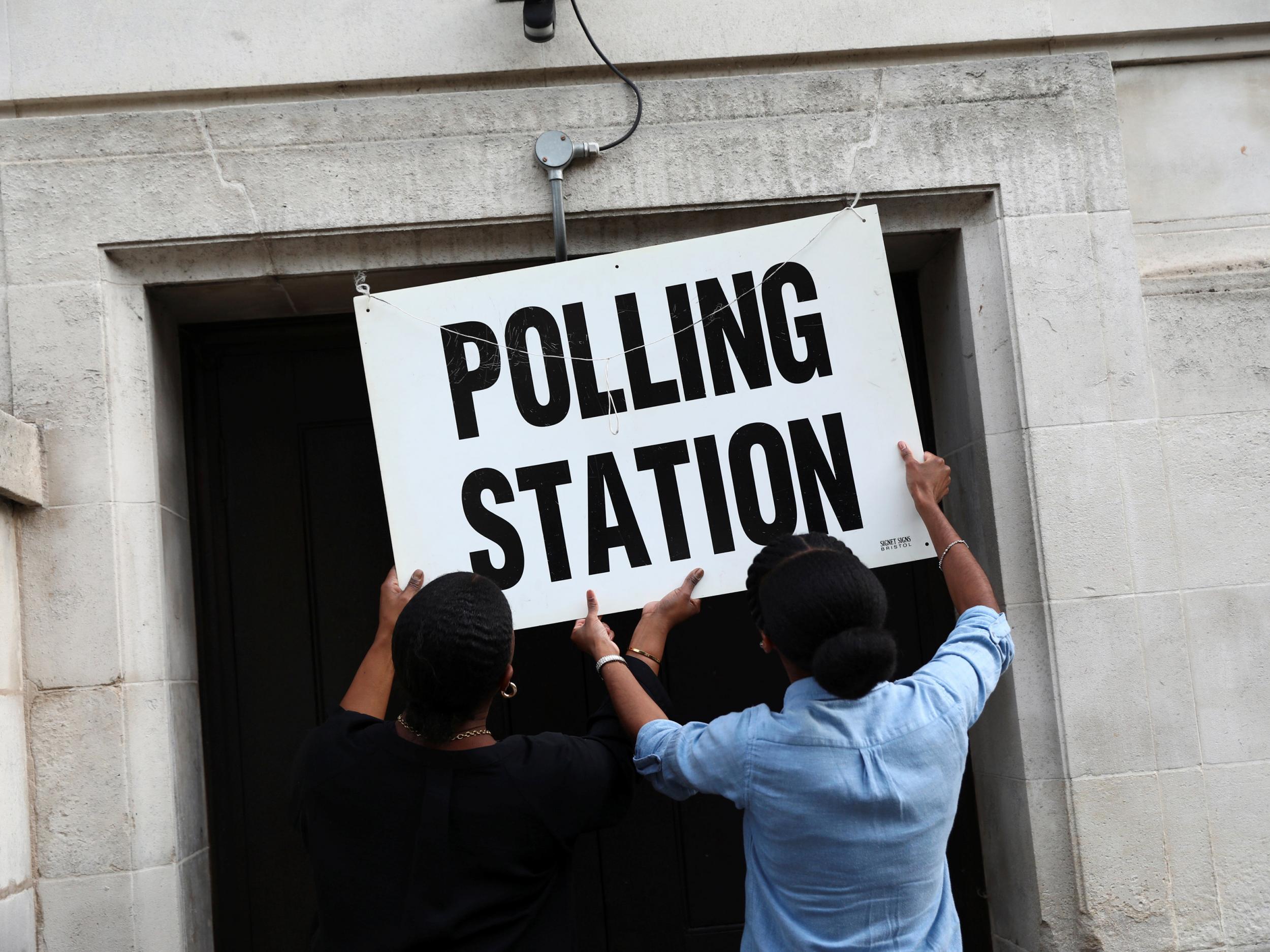 Workers prepare signs outside their polling station on general election day in London